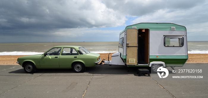 Classic Vauxhall Chevette Car towing Small Trailer - caravan on seafront promenade beach and sea in background