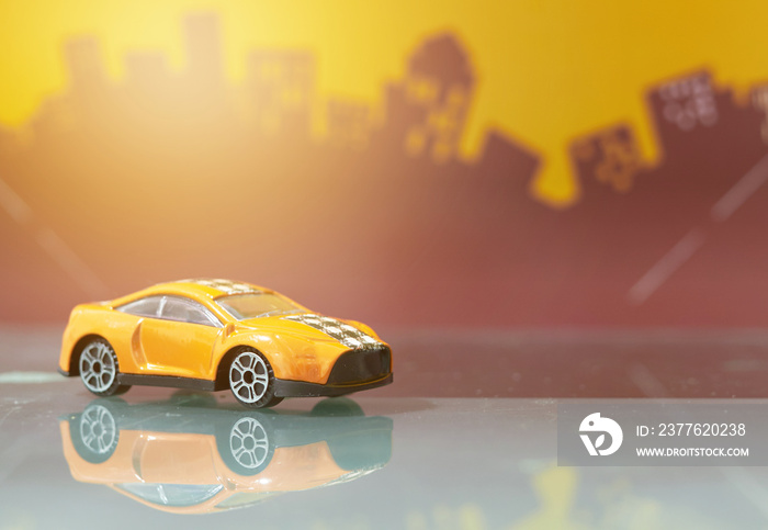 Orange saloon car toy selective focus on blur city background