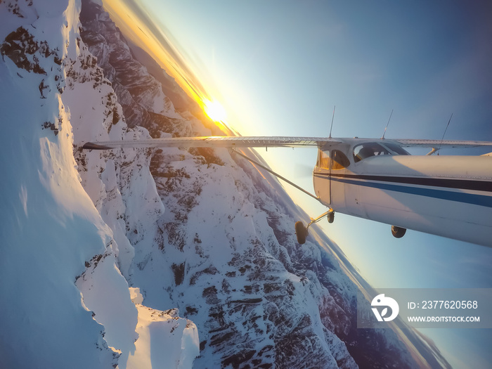 Small airplane flying near the rocky Candian Mountains during a vibrant sunset. Taken North of Vancouver, British Columbia, Canada.