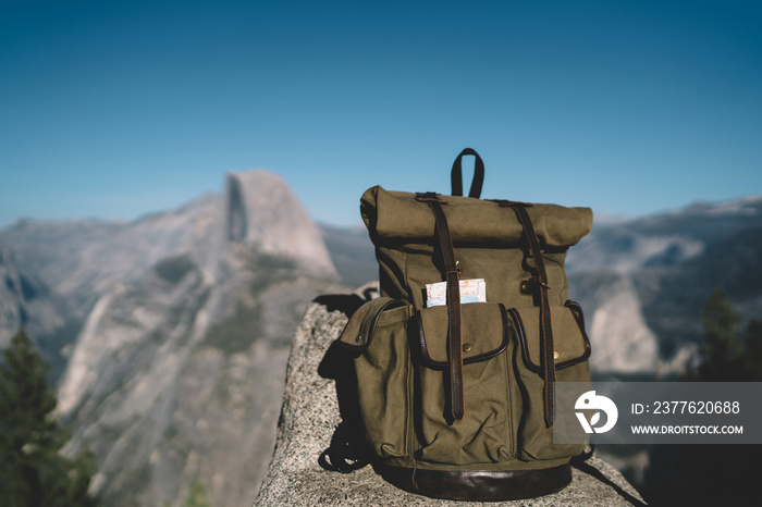 Picture of large khaki backpack with equipment and pockets with map for travel holidays and hiking tour, rucksack with stuff for exploring and tourism in natural wild environment on landscape