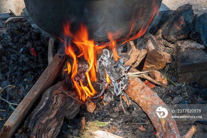 A stove on a campfire and the pot on it.