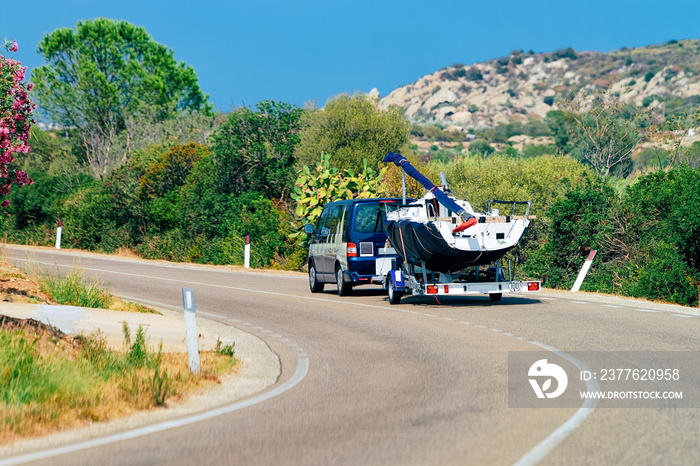 Car with yacht or motor boat in road in Sardinia