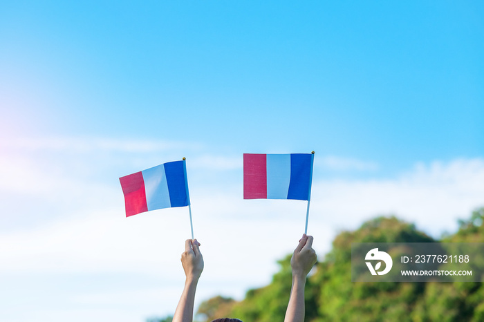 hand holding France flag on blue sky background. holiday of French National Day, Bastille Day and happy celebration concepts