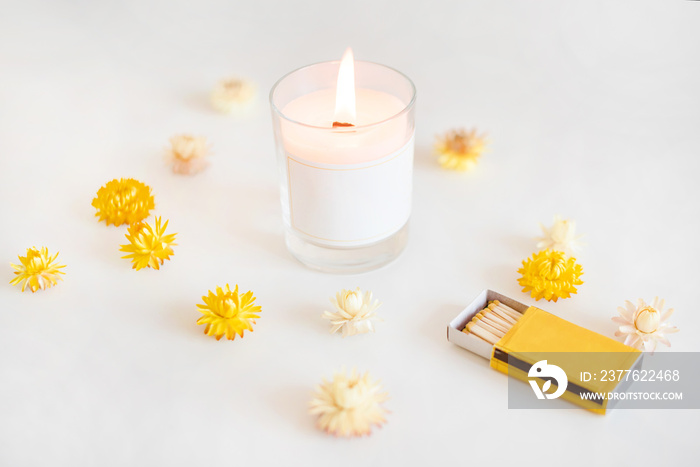 Wooden wick candle with matches and yellow flowers. Elegant home decoration. Burning wax scented candle.