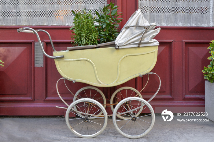 Old vintage baby stroller outdoors with plants