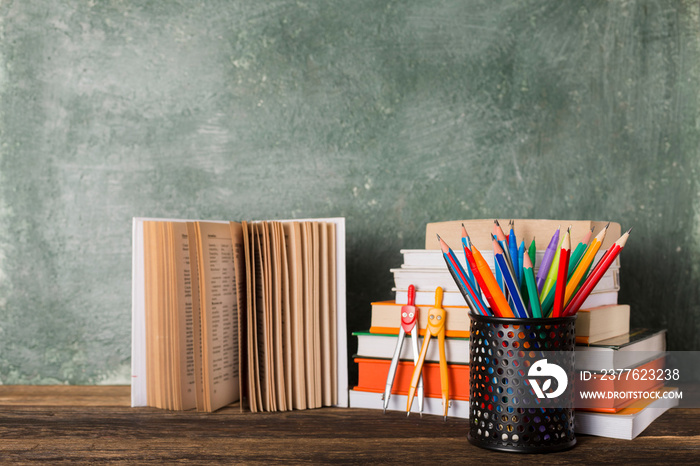 Stack of books and stationery on the background of the school board. Education and back to school concept.