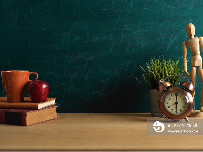 Study table with books, cup, apple, decorations and copy space in blackboard background