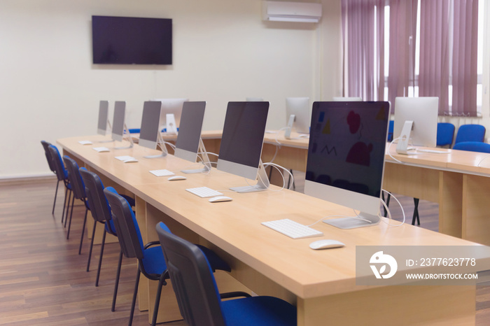 Modern office with computers on desks. Empty computer room in college. Interior of classroom with computers. Concept of corporate working space.