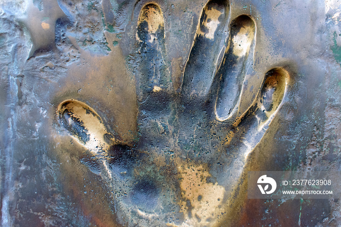Prints of human hand. The imprint of the left palm on the surface of bronze close-up.