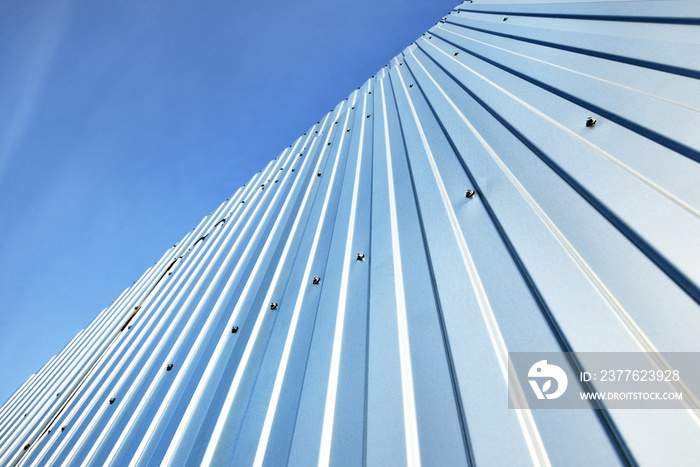 Low angle view of the silvery warehouse wall. Metal siding, texture, close-up