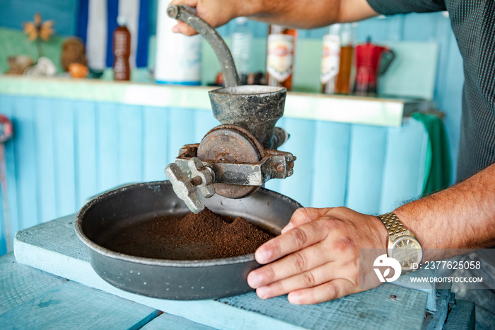 Cuba: Man grinds with an old coffee mill