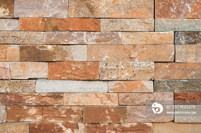 Brown with orange stone wall tiles texture.wall natural brown stone dirty,dust with pattern design or abstract background.