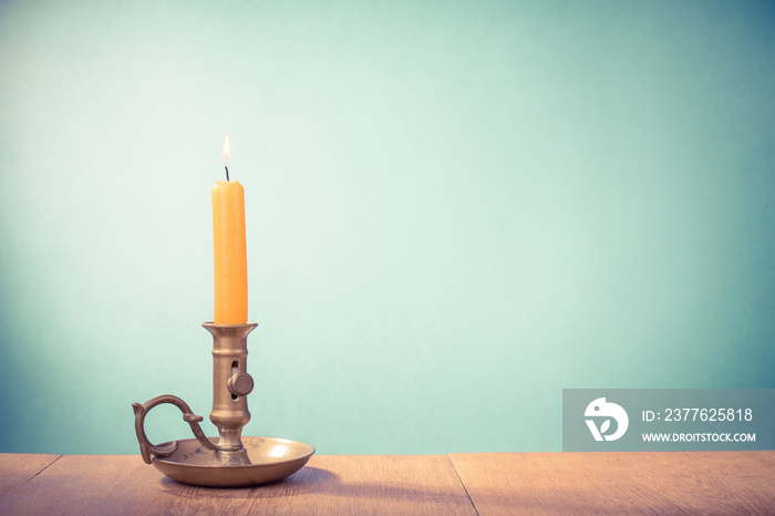 Vintage old bronze candlestick with burning candle. Retro style filtered photo