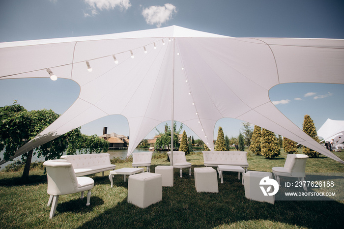 banquet table setting under a white tent on the grass