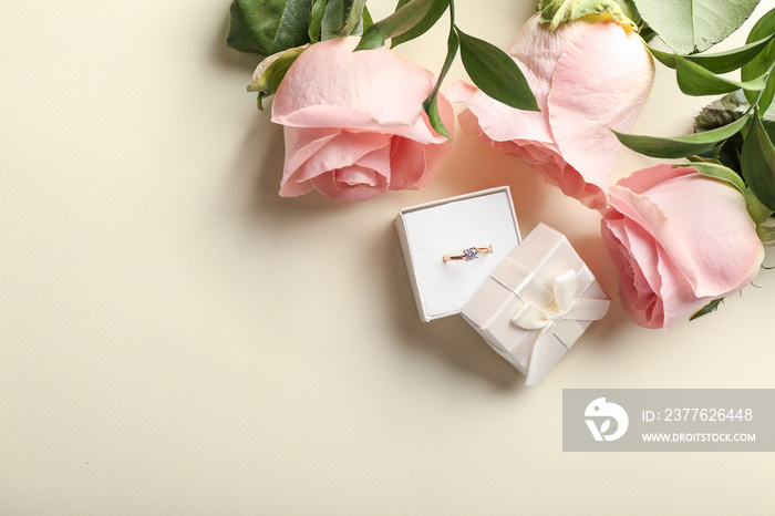 Box with beautiful engagement ring and roses on light background