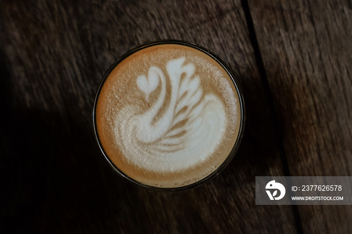 A cup of coffee latte, flat white with swan shape latte art on wooden table, top view