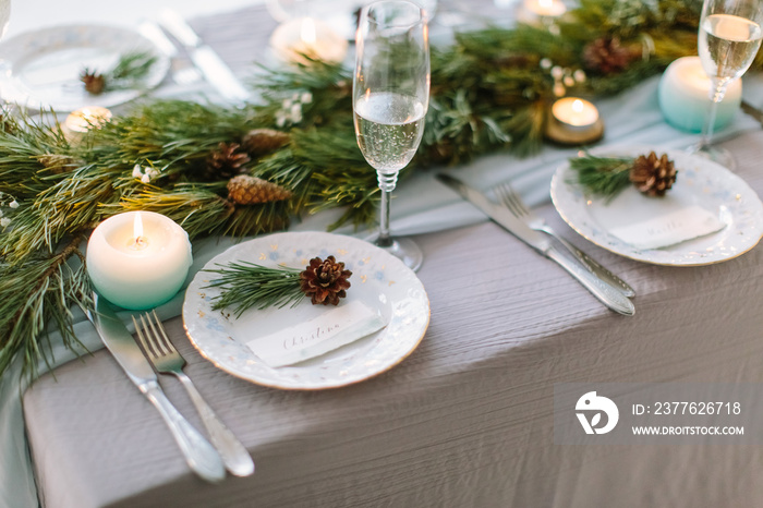 Aerial view of winter green garland on a wedding table with white plates and and blue candles