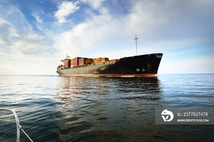 Large cargo container ship leaving the port of Norfolk, close-up. Cloudy blue sky. Virginia, USA