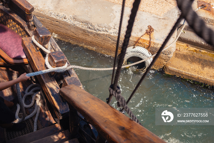 White rope securing wooden boat to city dock