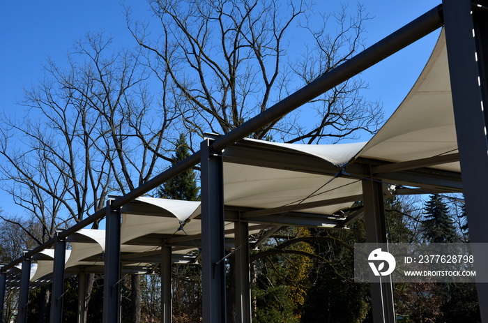 white canvas stretched, shading from the sun and rain over the terrace of the restaurant, on the playground in the kindergarten, on the platform of the promenade. pergola with metallic gray beams