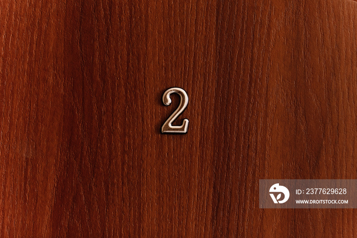 Golden number two sign on brown door of apartments. Closeup.