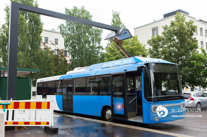 Electric bus at a stop is charged by pantograph