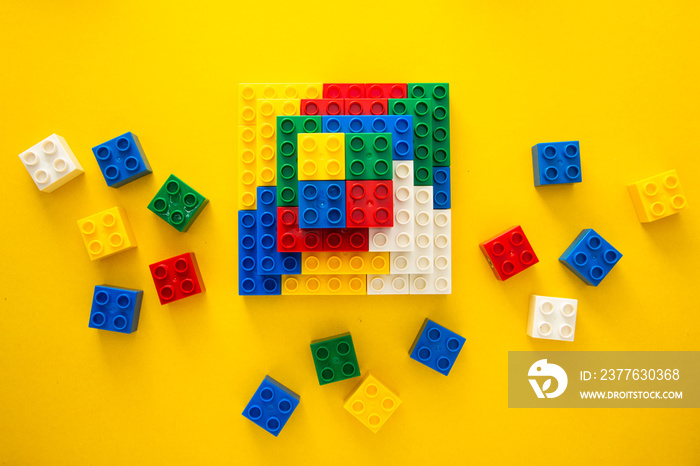 Color plastic building blocks on yellow background