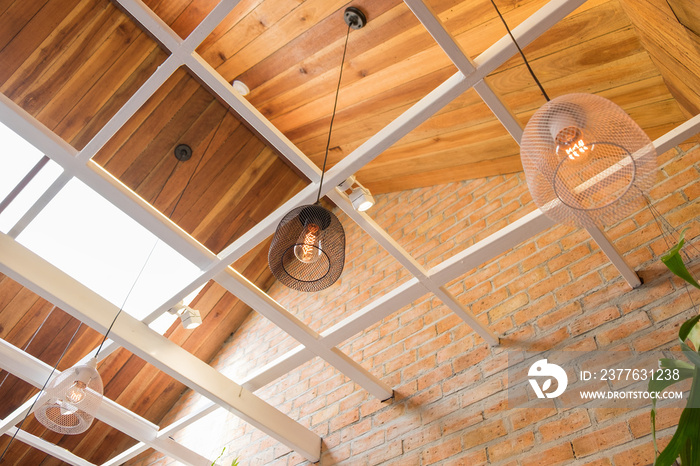 Side view of a cafe with modern black and white lamp hanging from a wooden ceiling. Brick walls style vintage in coffee shop