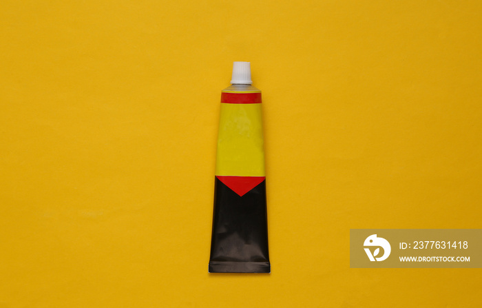 Tube of glue on a yellow background. Top view