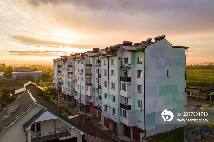 Top view of developing city landscape. Apartment building and suburb house roofs on pink sky at sunrise background. Drone photography.