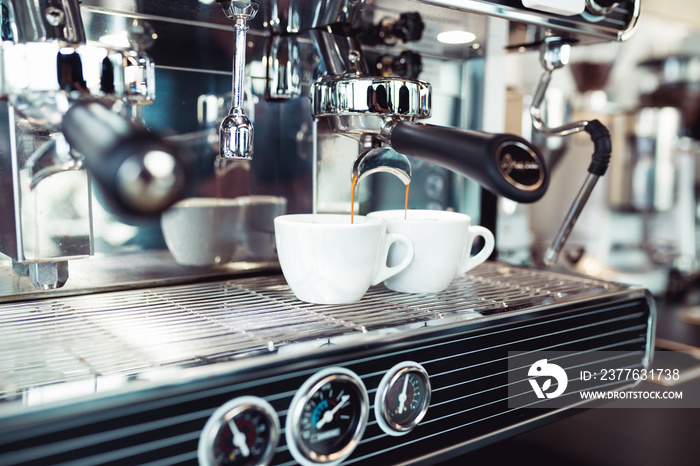 Espresso pouring from coffee machine into coffee cup.