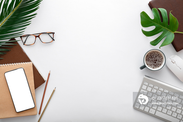 Modern work space with computer keyboard and office supplies. Empty mobile phone mockup on white table with tropical palm leaves. Frame Flat lay