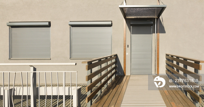 Metal blinds on the doors and windows of the facade of the house