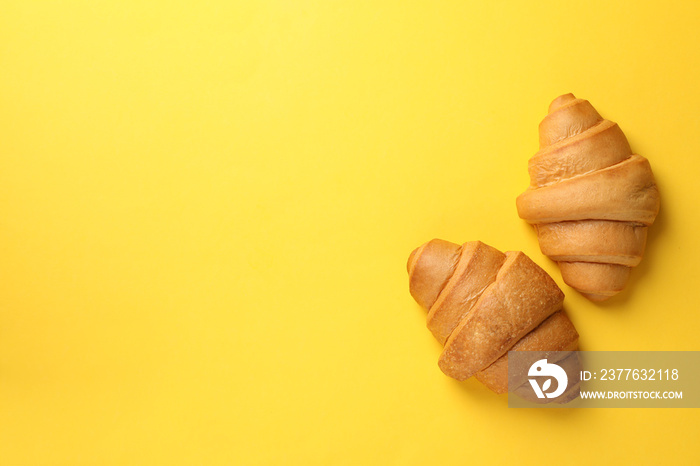 Baked croissants on yellow background, top view