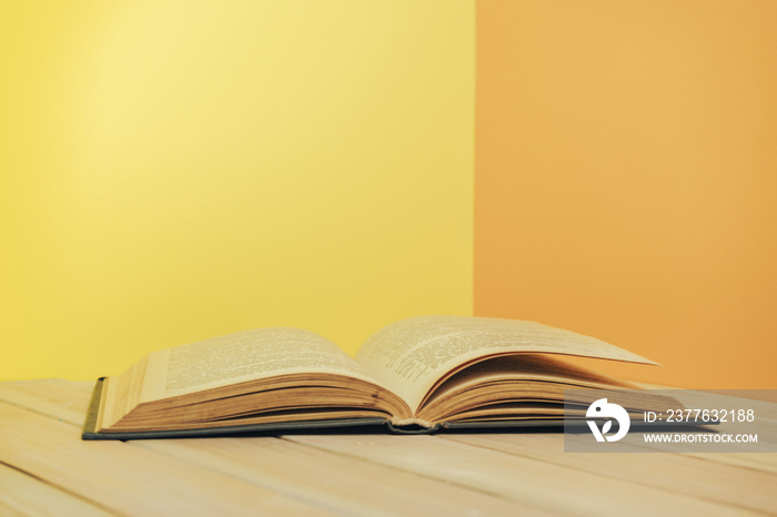 Beautiful book on a wooden table and yellow orange wall background.