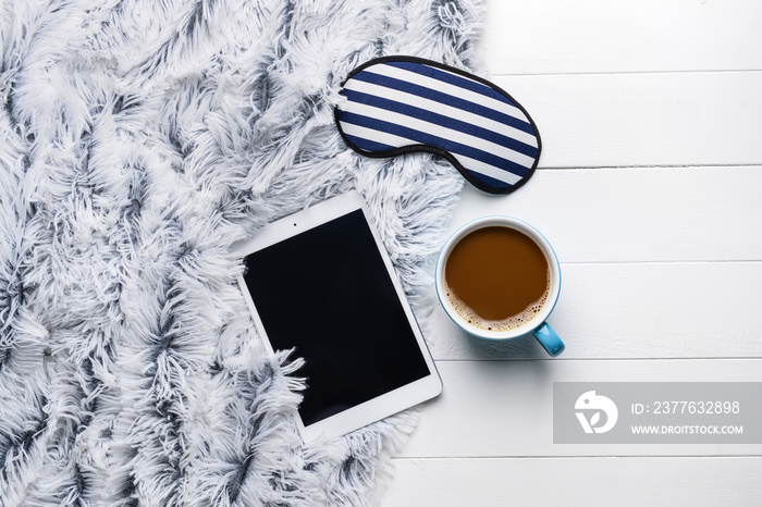 Composition with sleep mask, tablet computer and coffee on wooden background