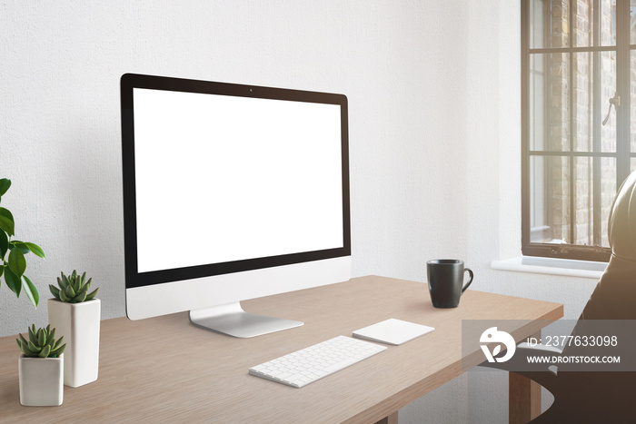 Workroom desk with computer display with isolated screen for mockup. Plants and cup of coffee beside.