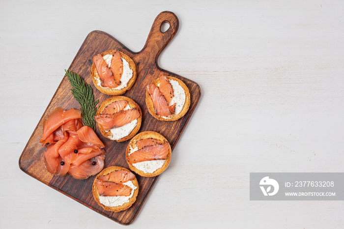 Festive appetizers with smoked salmon slices on wooden cutting board