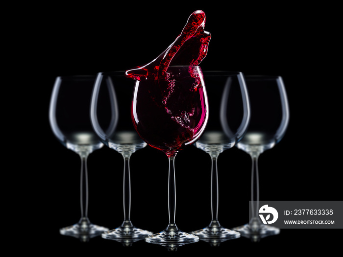 Set of empty glasses for red wine with splashes in a row isolated on black background.