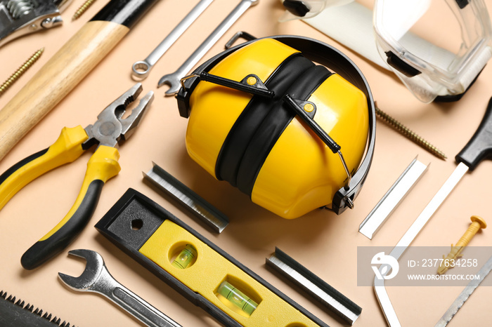 Builder’s tools with hearing protectors on beige background