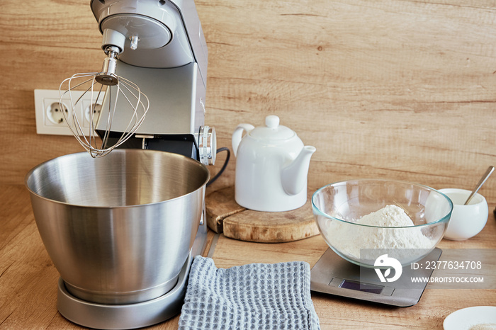 Stand electric mixer with whisk nozzle and ingredients for cake in the kitchen. Kitchen appliances