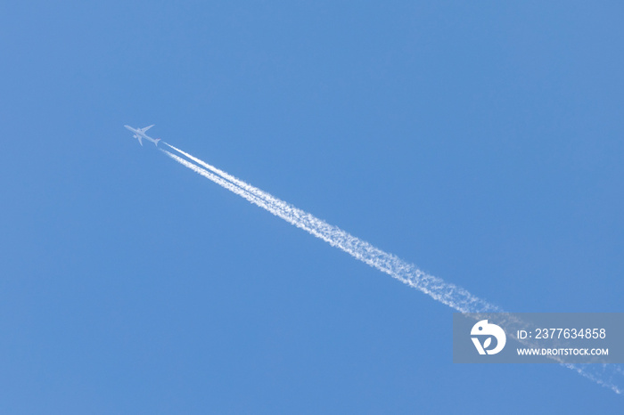 aviation, travel by airplane, airplane flying on a sunny day, sky without clouds, and leaves a large jet stream behind