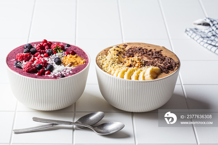 Chocolate and berry smoothie bowls on white background. Raw vegan food concept.