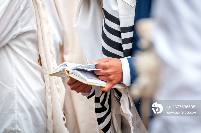 Hands and prayer book close-up. Orthodox hassidic Jews pray in a holiday robe and tallith.