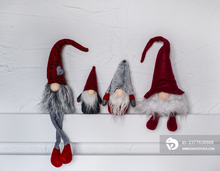 Cute Christmas gnomes. Elf Christmas decorations. Four gnomes in a red hats sit on a wooden shelf. Christmas and New Year concept, greeting card