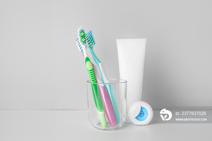 Holder with tooth brushes, paste and floss on white background