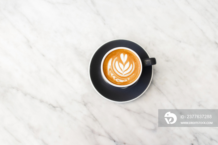 Dark gray cup of fresh cappuccino with classic latte art on white marble table trendy background. Empty place for text, copy space. Coffee addiction concept. Top view.