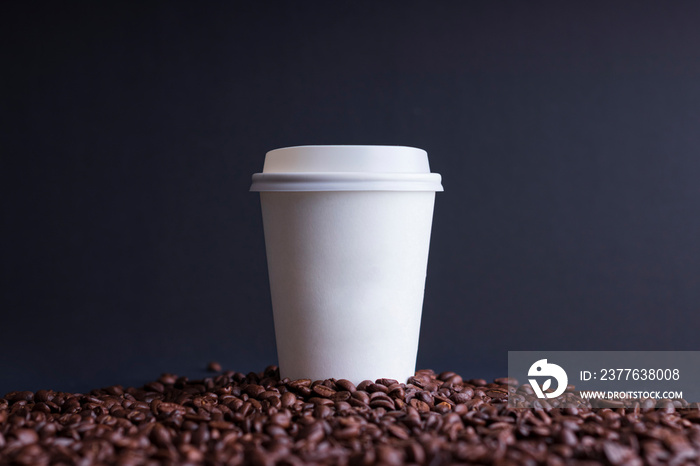 paper coffee cup among roasted coffee beans, on black background