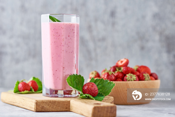 Strawberry milk shake in a glass jar and fresh strawberries with leaves