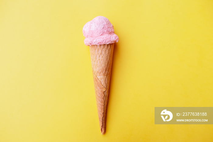 Close up strawberry ice cream in waffles cone against yellow background. Copy space.